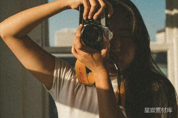 高清摄影 穿着白色背心的女人手里拿着黑色的单反相机。