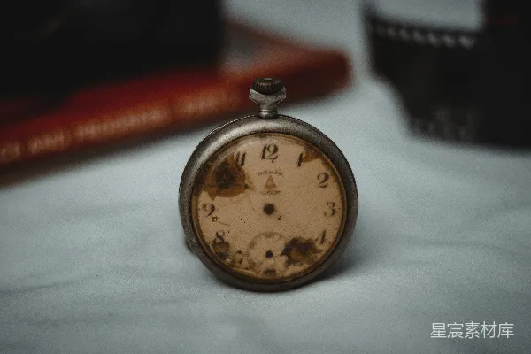 高清摄影 一只怀表放在桌子旁，旁边有一本书。