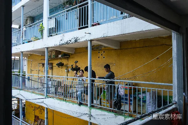 高清摄影 在一座多层建筑的黄色墙壁阳台上的人们。