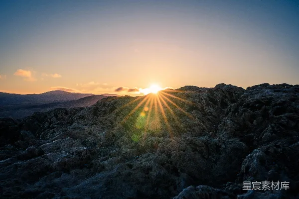夕阳西下，落在一片岩石山头之上。