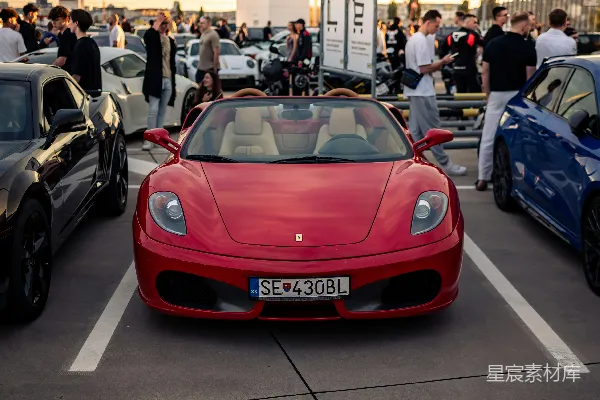 红 Ferrari 在日落时和其他汽车一起停着。
