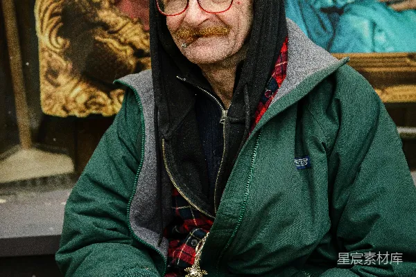 一个戴着眼镜和留着小胡子的老人坐在外面。