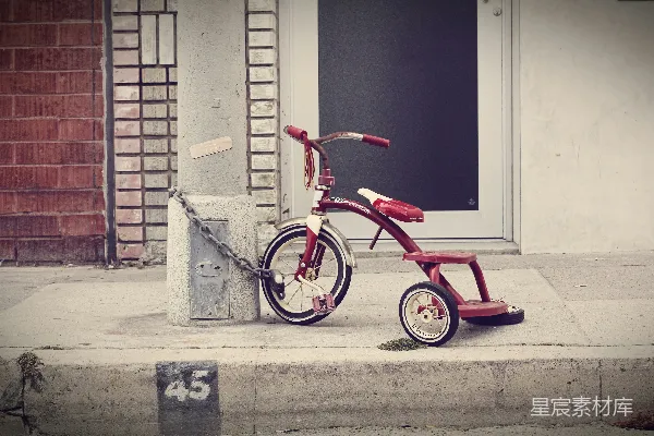红色和白色的Radio Flyer三轮车用铁链拴在石柱上