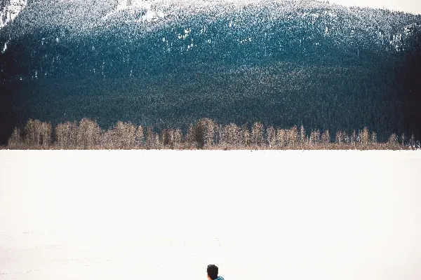 身穿蓝色泡泡状拉链夹克和长裤的人在白天的雪地里漫步。