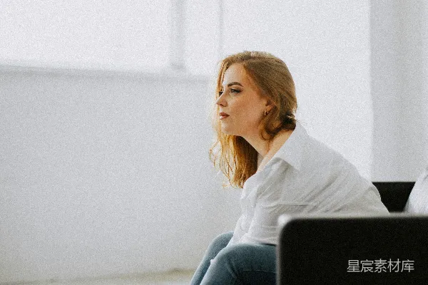 一个女人坐在一间白色的房间里沙发上。