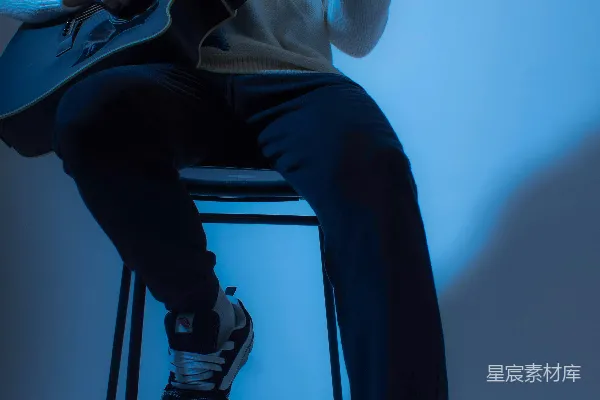 一个男人坐在凳子上拿着吉他