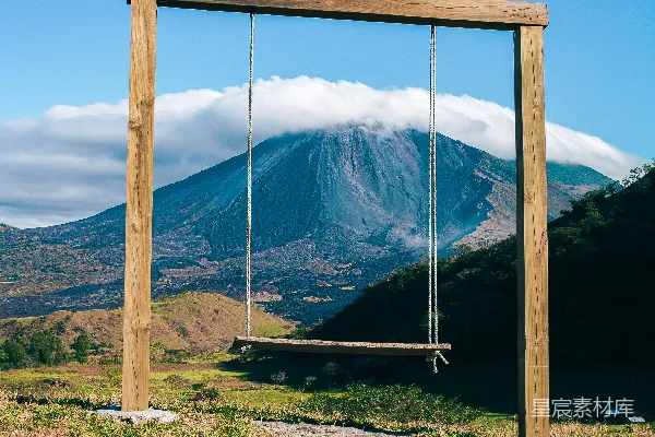 木制秋千架下，雄伟的火山云遮掩。