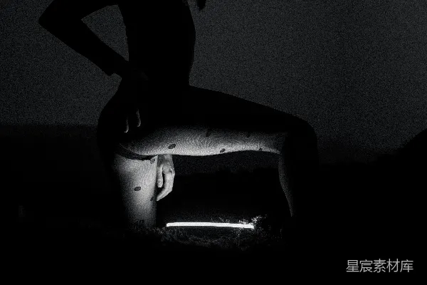 高清摄影 一个女人在黑暗中双腿交叉站着。