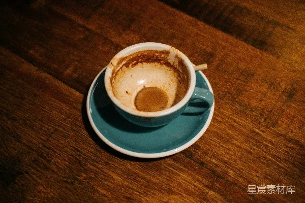 白色陶瓷杯中有一杯棕色液体放在蓝色托盘上