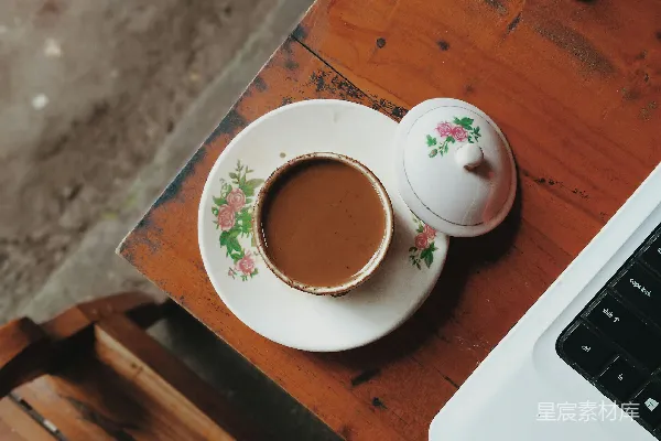 咖啡杯放在笔记本电脑旁边的一个托盘上