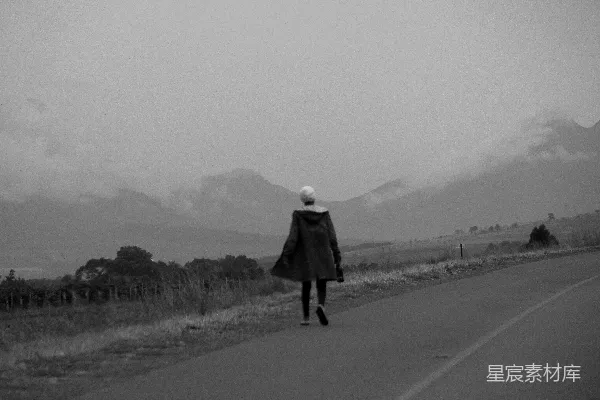 高清摄影 一个女人走在一片荒野中的道路上。