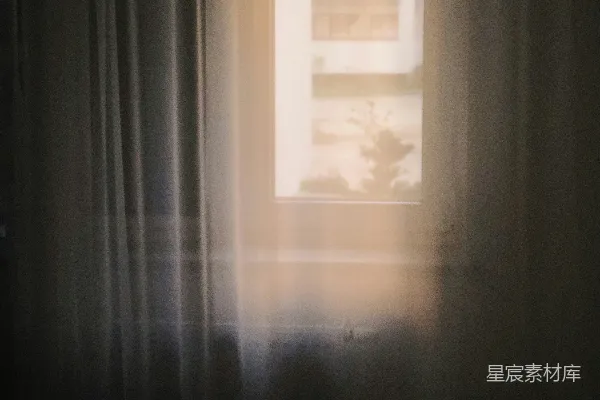 黑暗房间中一扇窗户挂着白色窗帘