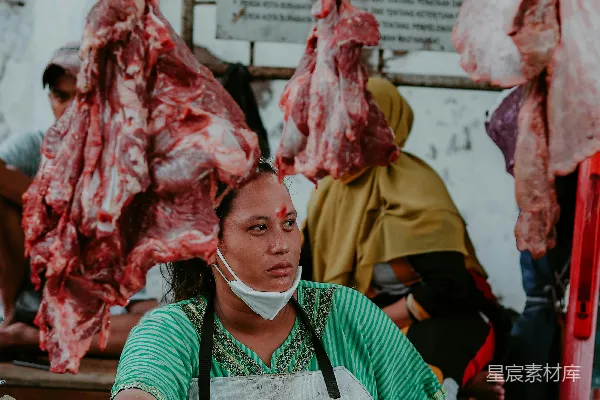 一个女人站在桌子旁边，桌子上摆满了肉。