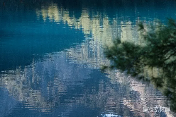 暮色中平静的湖水映照着山峦和树木。