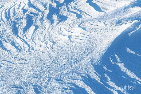 阳光下，雪堆被风吹塑成各种图案。