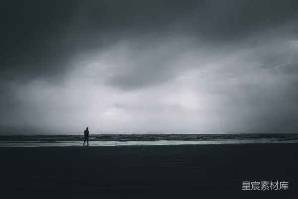 高清摄影 一个人站在海滩上，天空多云。