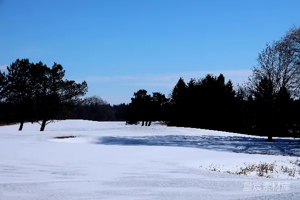 白雪覆盖的高尔夫球场坐落在晴朗的天空下。