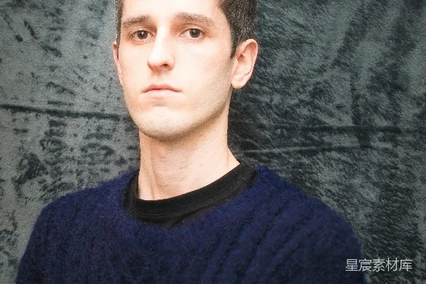 身穿蓝色毛衣的男人正在拍照。