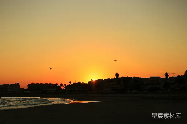 夕阳西下，海滩与建筑之间。