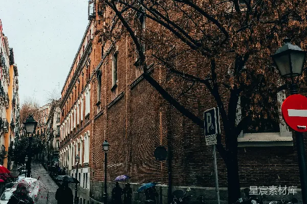手持雨伞的人走在建筑物之间行走