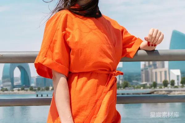 橙色连体衣女子傍水而立