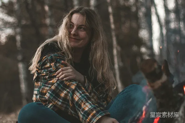 穿着蓝色牛仔裤的女人坐在地上，旁边是一只棕色的狗，时间是白天。