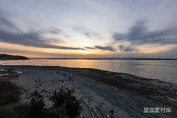 夕阳下绿色草地旁的白沙近水处