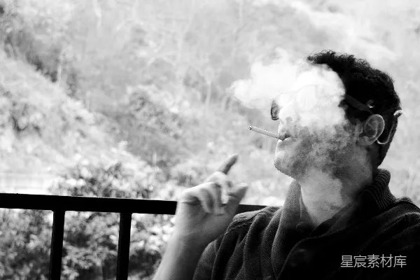 高清摄影 一个男人在阳台上抽着香烟。
