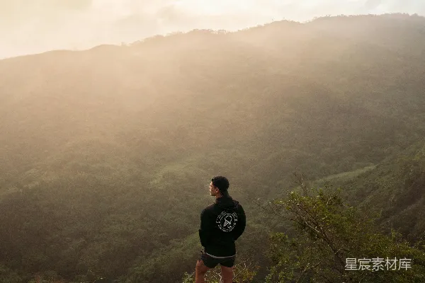 黑色上衣的男人站在棕色岩石山顶部的白天