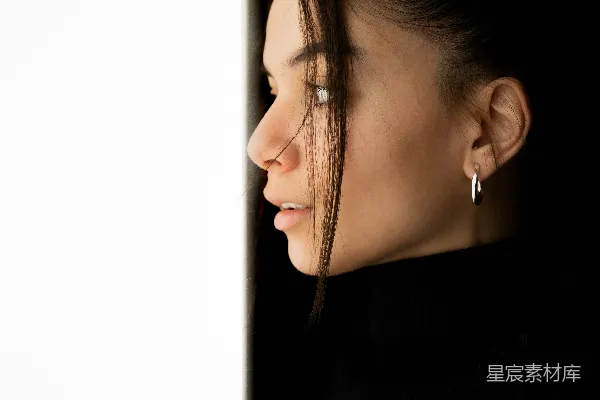 高清摄影 一位女士正从一堵白色的墙外向外看。