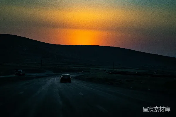 汽车行驶在通往一片绚烂夕阳的路上。