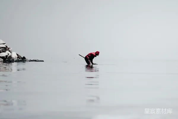高清摄影 一个人站在冲浪板上在水里。