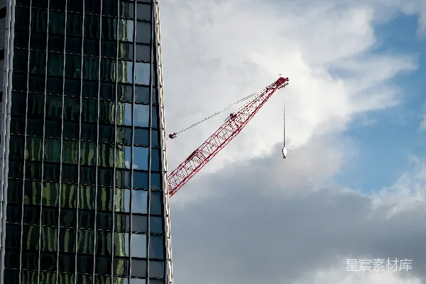 起重机矗立在玻璃建筑附近的阴天中