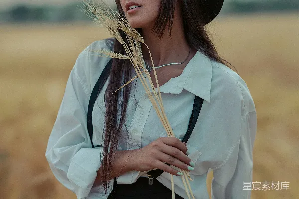 一个戴帽子的女人手持一束小麦