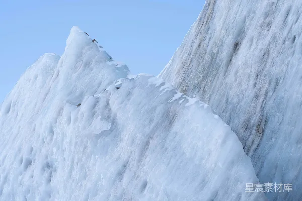 山顶上站着一个人，身下是覆盖着白雪的山峦。
