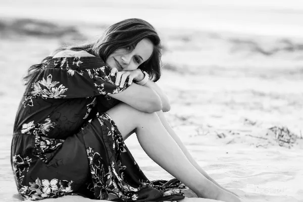 高清摄影 穿着黑白花裙子的女人坐在海滩上