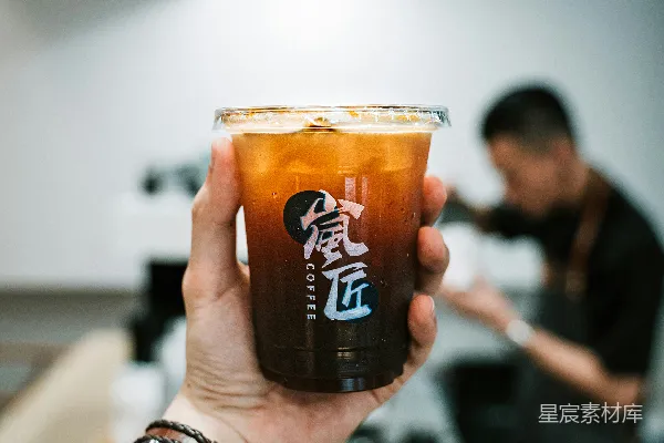 手持透明酒杯的人拿着一杯棕色液体
