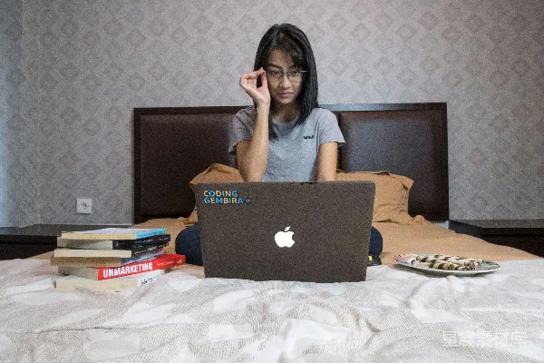 灰T恤的女人坐在MacBook前⾯。