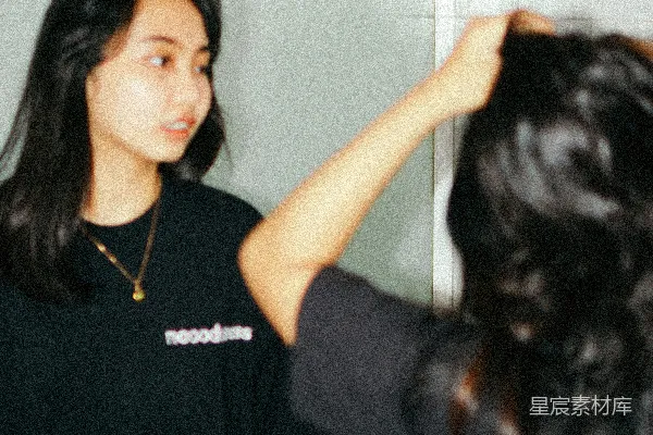 一个女人站在镜子前梳头发
