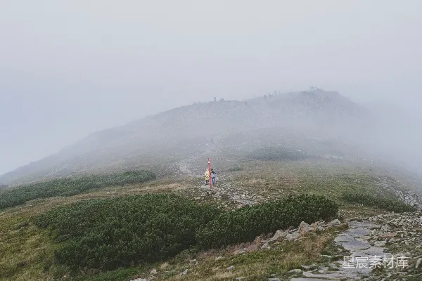 一个人站在一个近似水面的岩石上，在有雾的日子。