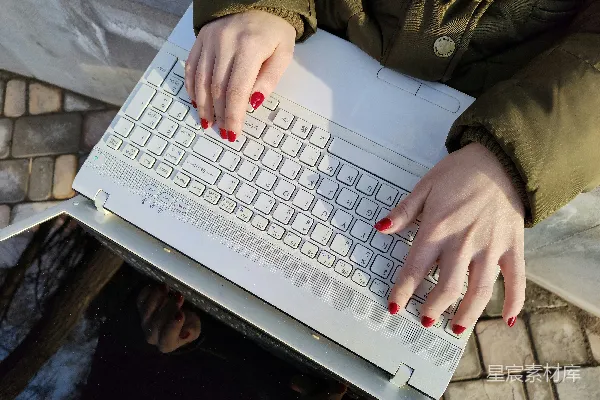 一个女人正在外面一台笔记本电脑前打字。
