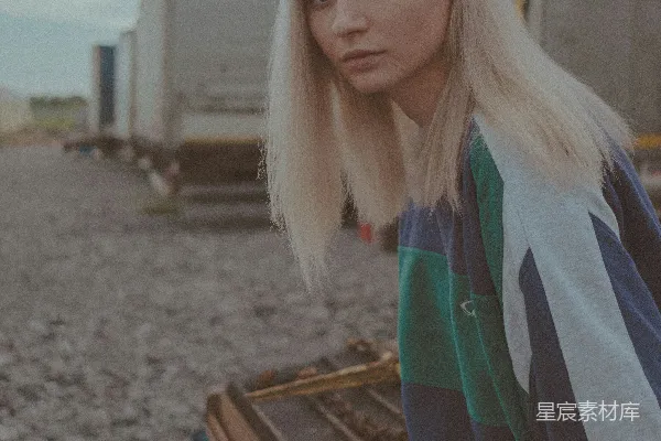 蓝黑夹克的女人在白天站在灰色的沙滩上