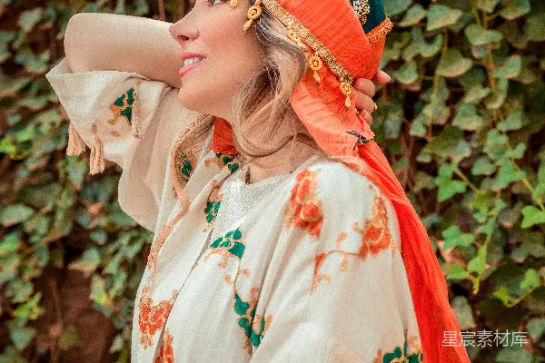 一个白衣女子，头上围着橙色的头巾。