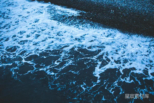 高清摄影 一片黑沙海滩，海浪拍打着它。