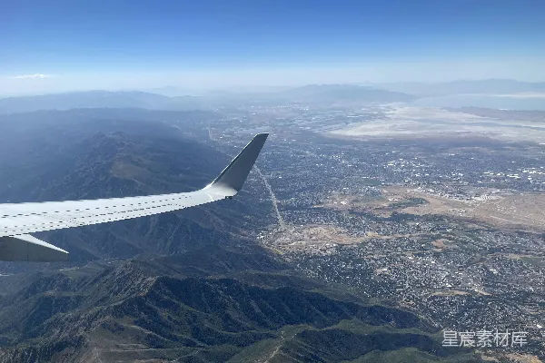 高清摄影 一架飞机在空中高飞，背景是山脉。