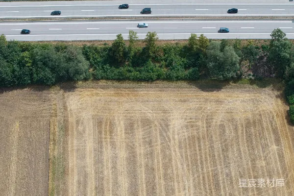 高清摄影 公路沿着树木和收获过的田地延伸。