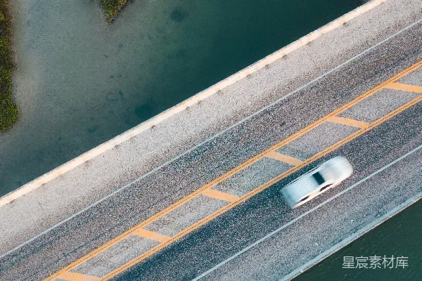 高清摄影 桥上有一辆汽车，桥下是河流和绿地。