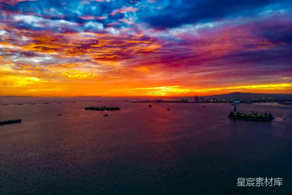 高清摄影 海洋上绚丽的夕阳，远处的城市灯光闪烁。