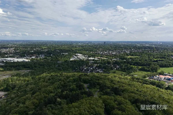 高清摄影 云层密布的天空下，覆盖着森林的山丘和远处的城市区域。