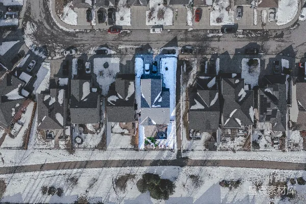 高清摄影 雪覆盖的住宅区航拍图，其中有一栋房子被突出显示。